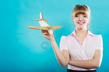 穿粉色衣服的女子手中拿着纸板飞机拍照图片