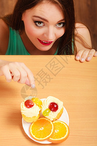 女人躲在桌子后面偷吃喝着美味的蛋糕上面有甜的奶油和水果美味的甜图片