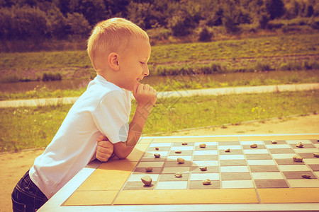 小男孩在公园玩跳棋图片