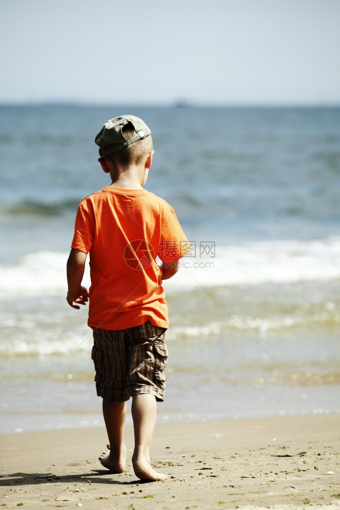 小男孩在海滩上背着景的图片