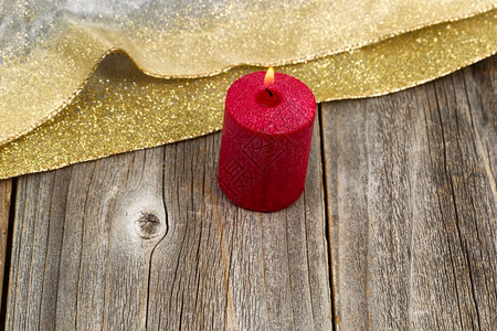 红蜡烛紧燃烧在生锈的木材上贴金丝带有选择地关注蜡烛前部和火焰有选择地关注圣诞节和新年的概念背景图片