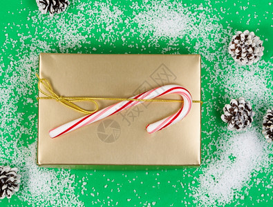 高角度的黄金礼物盒糖果甘蔗和松在轻雪绿色背景上图片