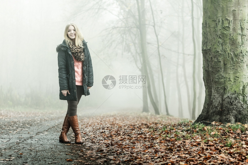 女人在浓雾的白天浪漫秋森林公园露户外走来放松有色长相照片图片