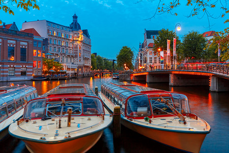 荷兰阿姆斯特丹运河桥梁典型荷兰码头房屋和船只的夜景图片