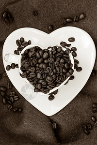 心形白杯满了棕色布面的烤咖啡豆背景图片