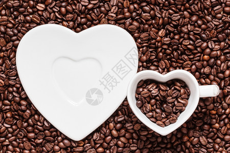 咖啡时间白色杯子和茶碟以烤咖啡豆背景的心形图片