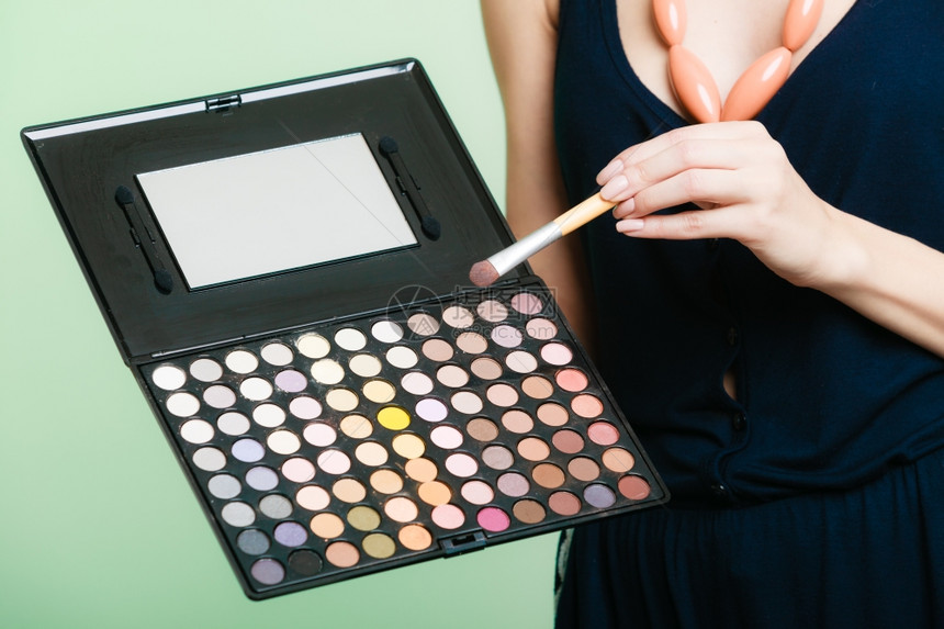 化妆美容程序和概念女拥有专业调色板和刷子的化妆品配饰工具的化妆品绿色背景图片