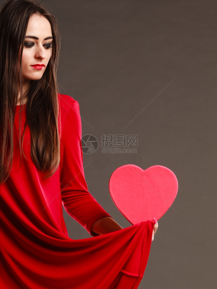 情人节爱浪漫概念红裙子的长发女美拿着心形礼物盒深灰色背景图片