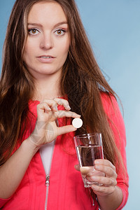 拥有止痛药和水的妇女保健持有晚期止痛药片和水杯的女孩头痛和疼图片