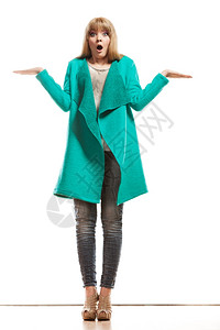 时装和广告概念全长的绿蓝色大衣全长的女绿蓝色大衣空手握着露的显示复制空间令人惊讶的面部表达方式被孤立背景图片