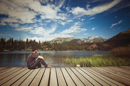 坐在高山湖岸上的人图片