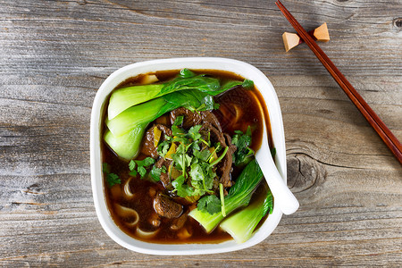 牛肉面汤的高角度视图汤里有筷子夹在生锈的木头上图片