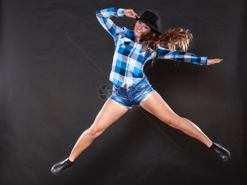 快乐和的女人跳跃玩得开心无忧虑的年轻女孩长发戴帽子检查衬衫和牛仔裤乡村风格的时尚图片