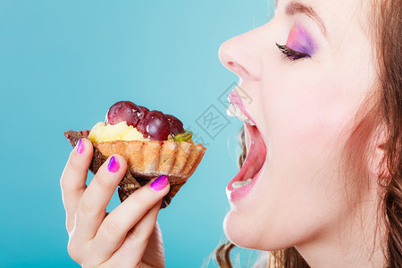 甜美的食物饱和脂肪的概念妇女面对张开的嘴吃蛋糕蓝背景背景图片