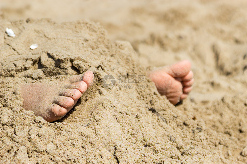 人类脚被埋在沙滩上夏季人类脚被埋在沙滩上暑假在海欢乐图片