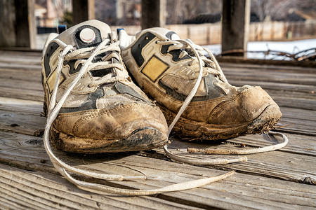 一双旧的泥巴鞋用木甲板对着跑图片