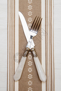 白色木背景的餐巾上刀叉和图片