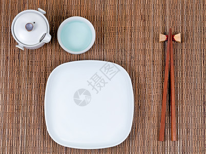 竹垫上的筷子板杯和茶叶服务器的俯视图片