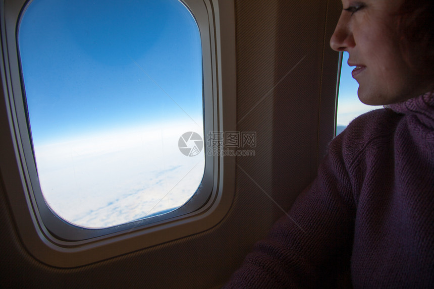 妇女坐在飞机窗口向外看图片