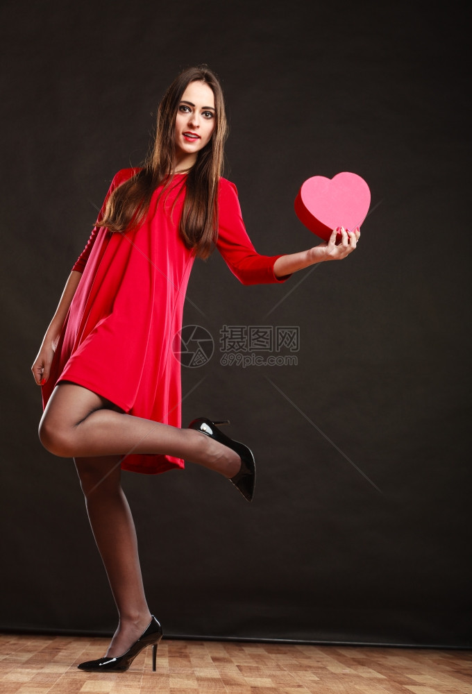 情人节快乐和关系概念穿红裙子的长发女郎带着心爱的象征穿着深灰色背景的舞姿图片