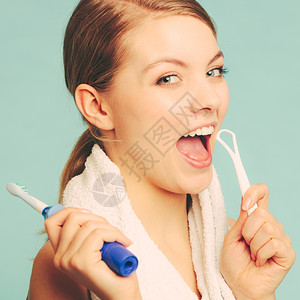 漂亮的年轻女孩有电刷和舌头清洁剂快乐的女士清洁她口腔关心牙科健康图片