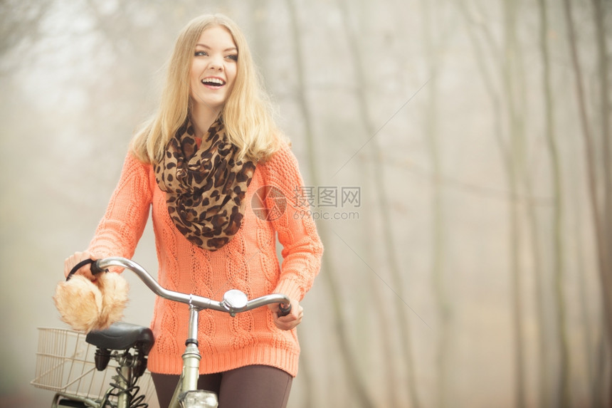 快乐的女子在雾中的公园里骑自行车图片