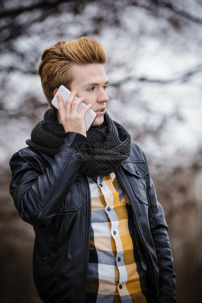 青年时装男在户外使用智能手机在移动电话上交谈图片