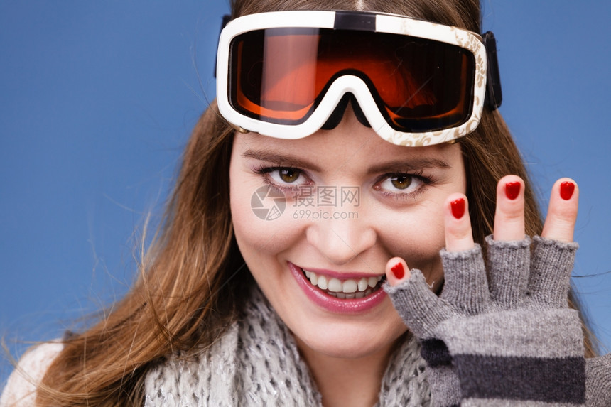 身着滑雪谷歌画像的女子滑雪孩身着谷歌画像的温暖服装冬季体育活动在蓝工作室露出手套和红指甲的漂亮女运动员拍摄图片