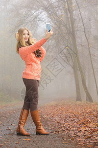 可爱的时装女郎在公园拍自照片可爱的时装女郎在秋天公园拍自照片图片