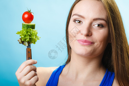 健康饮食和概念青春女子在蓝底拿着蔬菜工作室拍摄图片