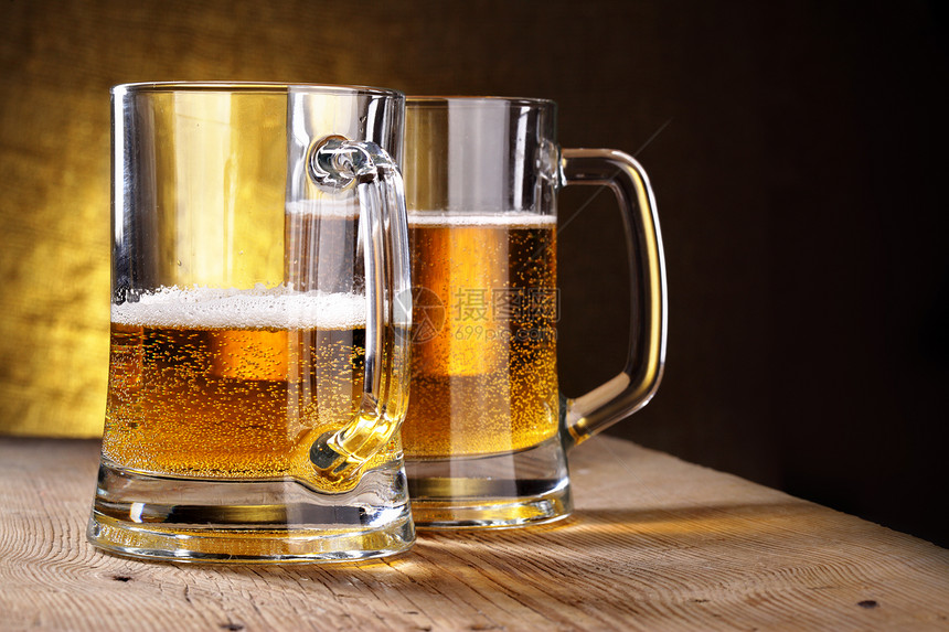 两杯啤酒木制桌上的两杯啤酒图片