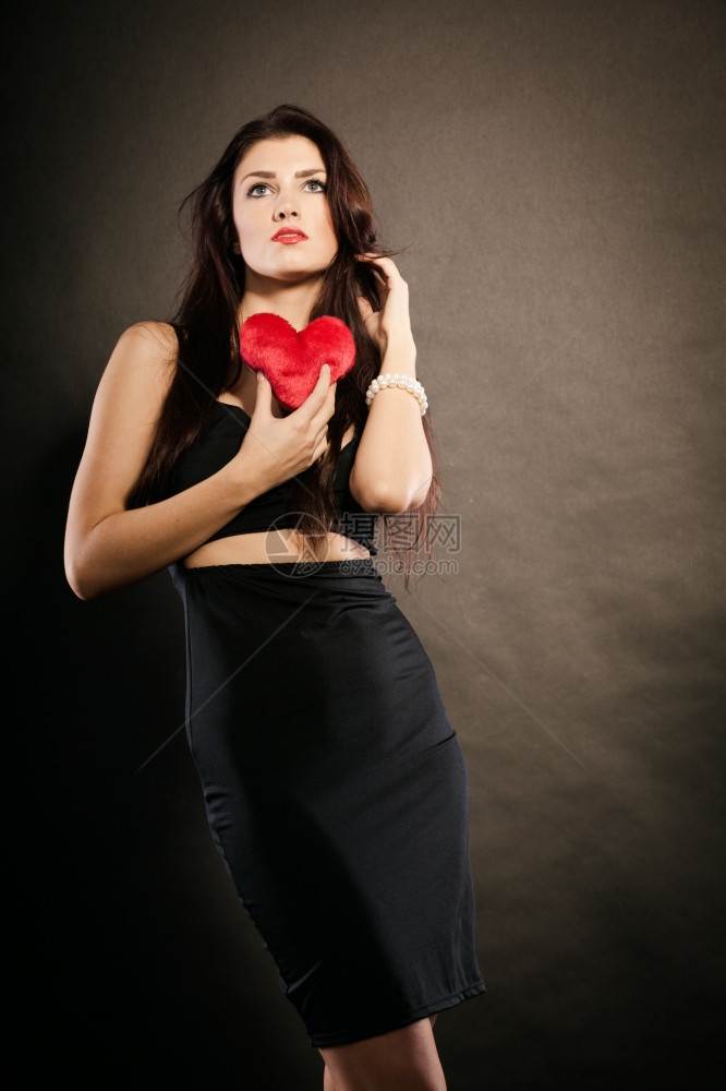 棕发长的女黑郎穿着色的感礼服拿着物形式是红心爱的象征画室在黑暗中拍摄图片