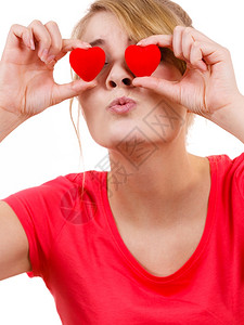 有趣的女人把红色心放在眼睛上笑的女孩把红色心放在眼睛上情人节爱幸福的概念背景图片