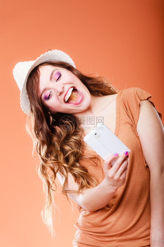 科技互联网与幸福概念快乐的暑期女拍摄自时使用智能手机相橙色背景图片