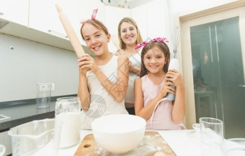 母亲和两个女儿在厨房摆姿势的肖像图片