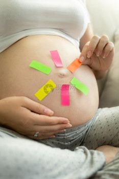 年轻孕妇从肚子上撕掉备忘录贴纸图片