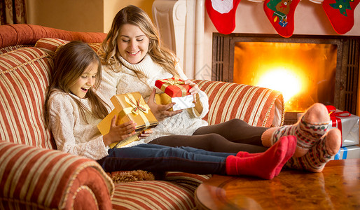 微笑的母亲和女儿在壁炉旁边拆开圣诞礼物图片
