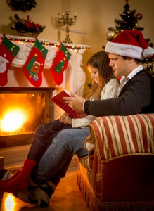 年轻父亲和女儿坐在壁炉里圣诞节前夕讲故事图片