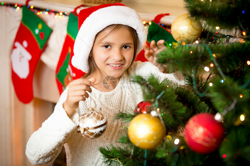 可爱的笑女孩近镜肖像装饰圣诞树和金球图片