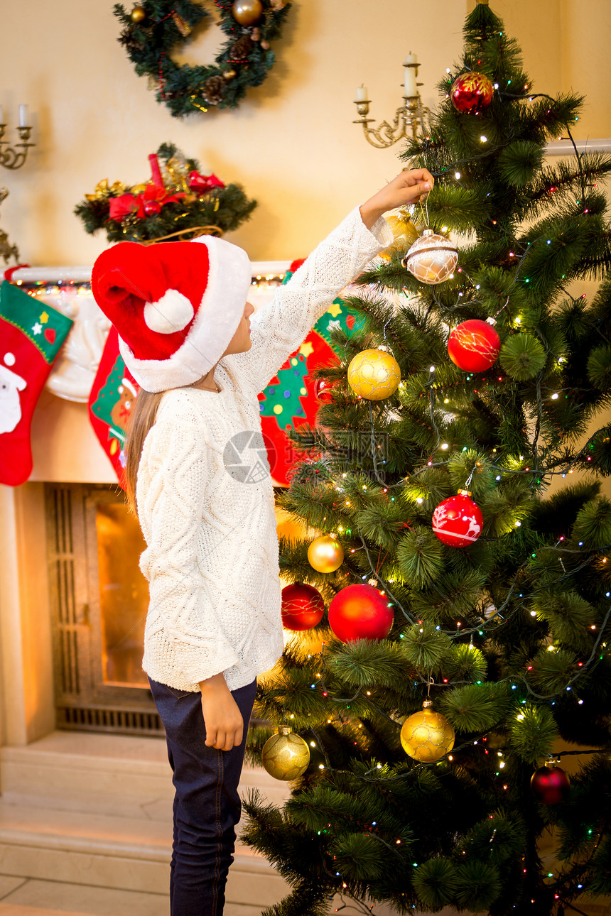 小女孩把装饰舞会挂在圣诞树上图片