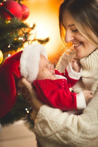 开心的母亲看着穿圣诞老人服装的男孩宝图片