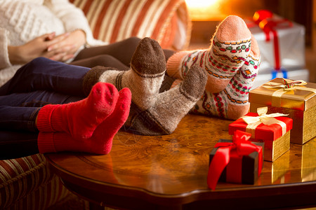 家庭圣诞节在壁炉旁边的羊绒袜子上双腿的近照图片