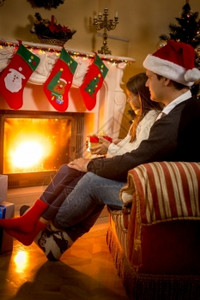 父亲和女儿坐在壁炉的椅子上圣诞装饰图片