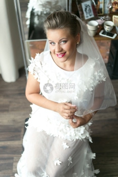 穿着白色礼带婚纱的美丽感新娘在家里装扮图片