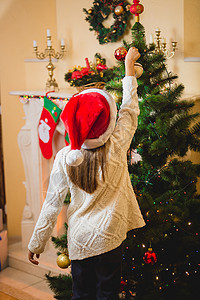 小女孩把装饰舞会放在圣诞树上图片