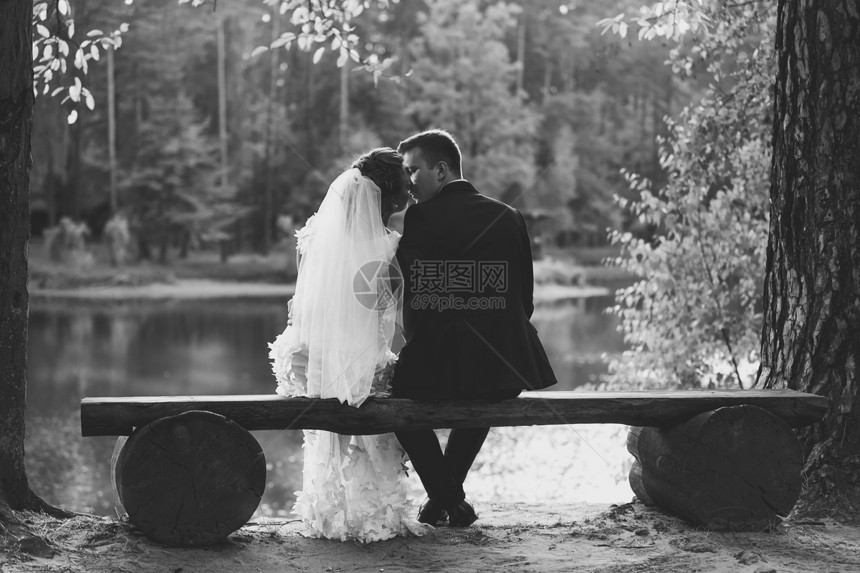 新娘和郎在河岸长椅上亲吻的照片图片