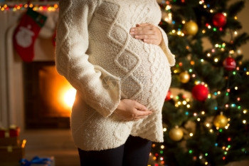 孕妇在壁炉和圣诞树上作假的近照片图片