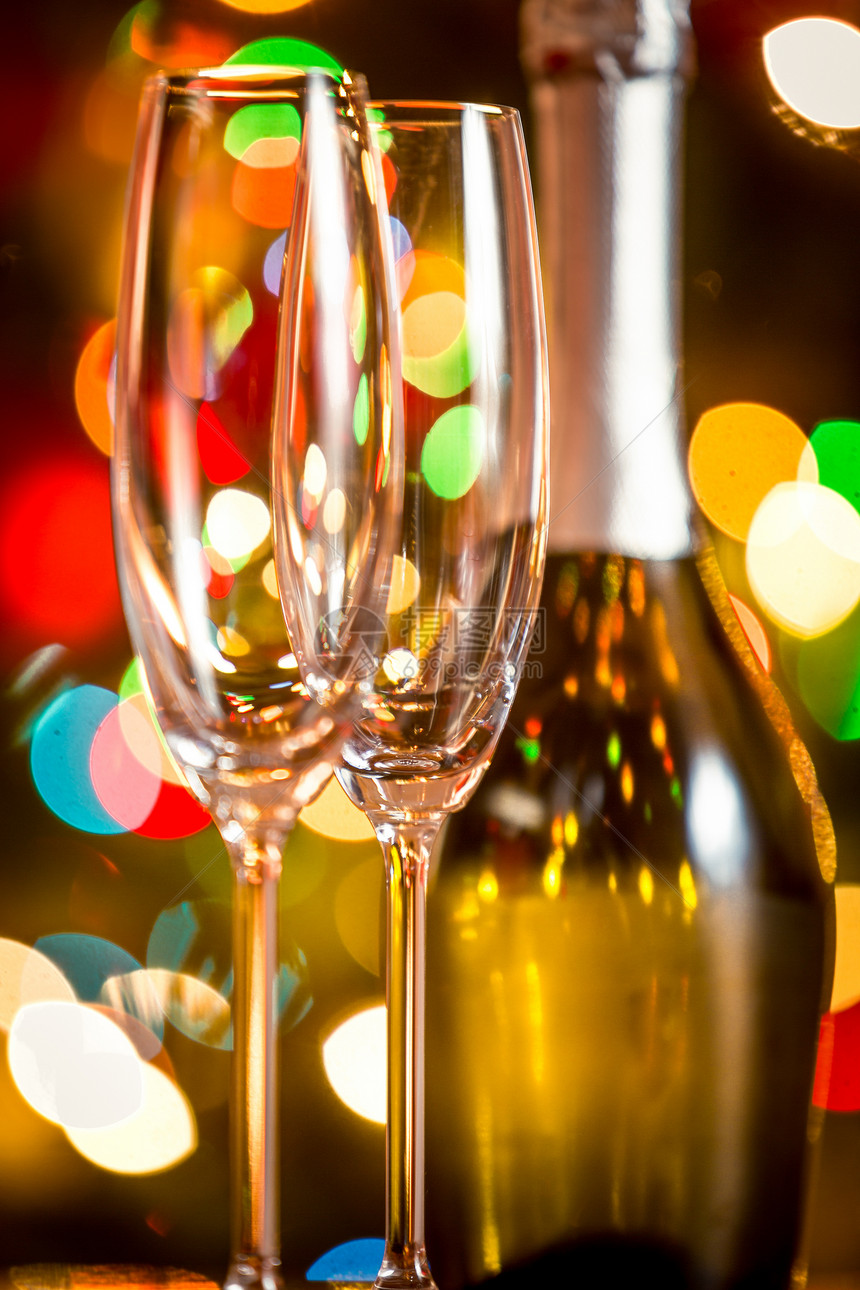两杯香槟和一瓶对抗闪亮的圣诞灯光图片