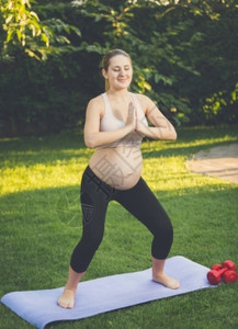 在公园做瑜伽锻炼的年轻孕妇图片