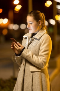 高雅女子晚上在街打短信的肖像图片